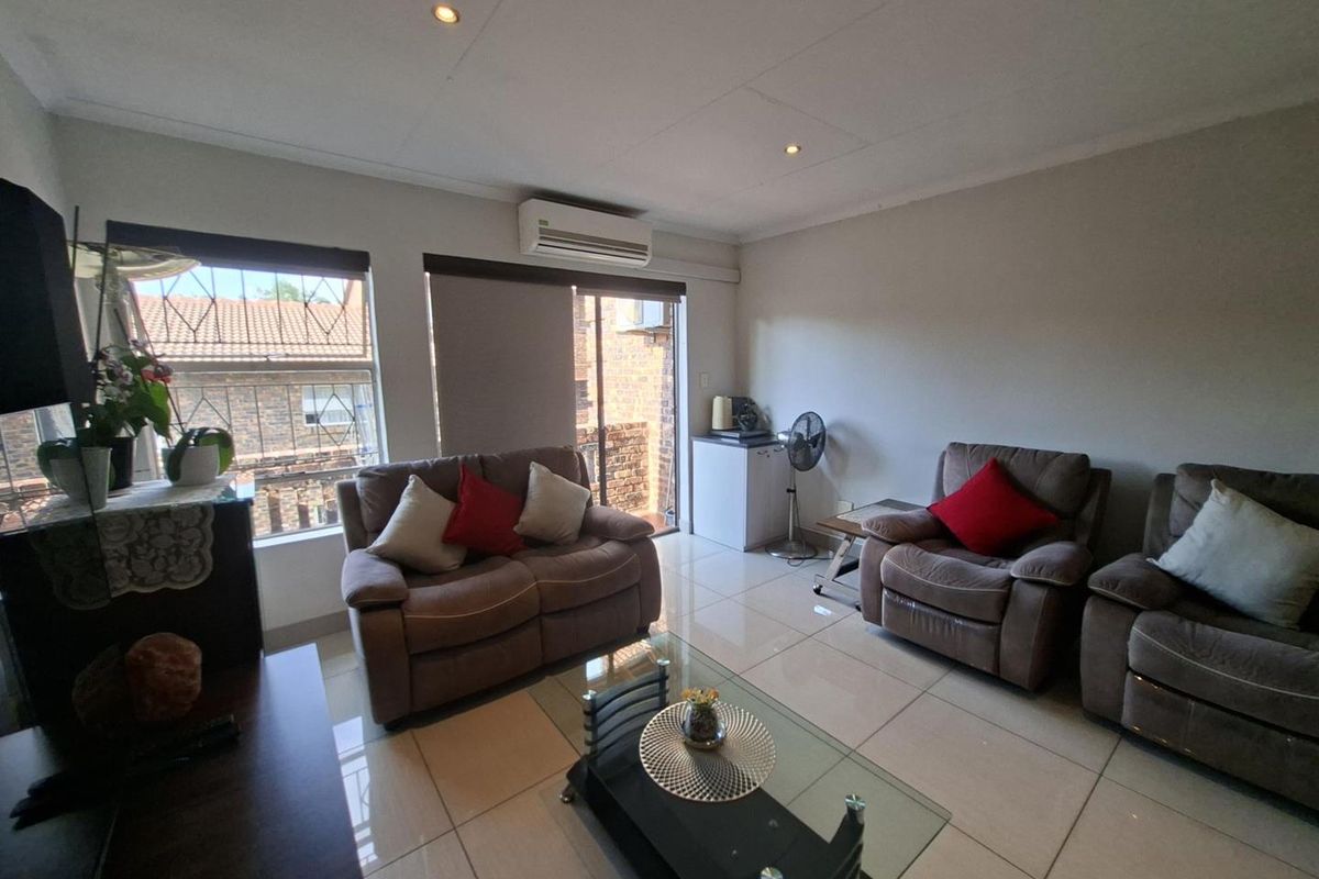 A bright living room featuring large windows, tiled flooring, recessed ceiling lighting, and a wall-mounted air conditioning unit.
