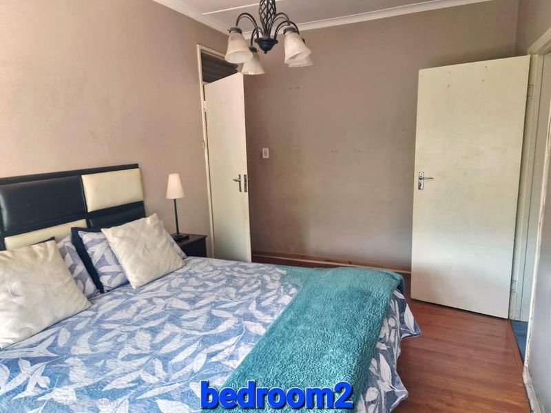 A standard bedroom featuring laminate flooring, neutral wall tones, and two internal doors, providing a functional and well-lit sleeping space.