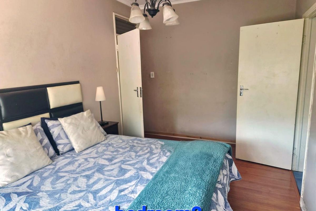 A standard bedroom featuring laminate flooring, neutral wall tones, and two internal doors, providing a functional and well-lit sleeping space.