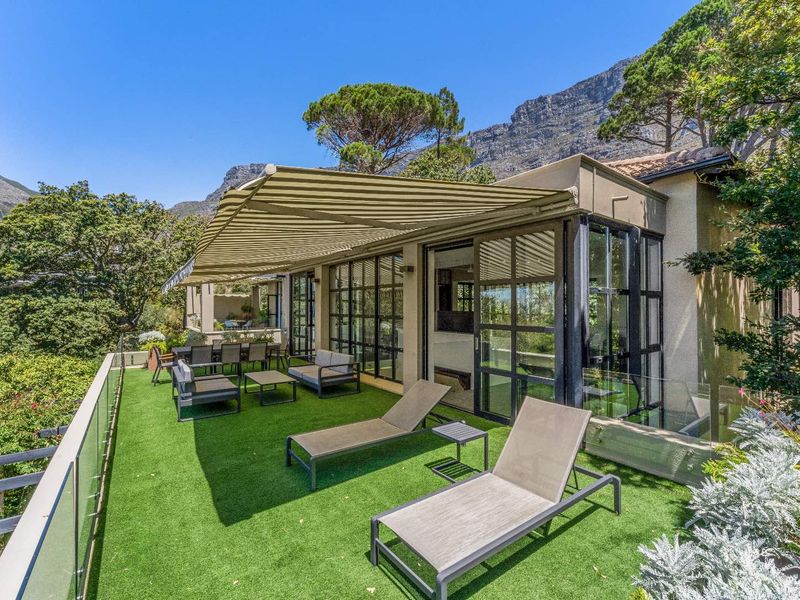Spacious outdoor patio featuring artificial turf, glass balustrades, and a retractable awning, offering a seamless transition from the interior living space.