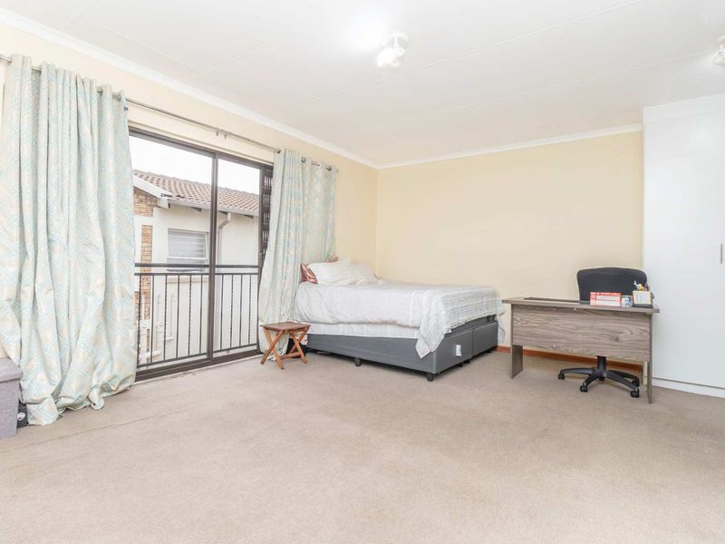 Spacious bedroom featuring neutral walls, carpet flooring, a built-in wardrobe, and a sliding glass door leading to a private balcony.