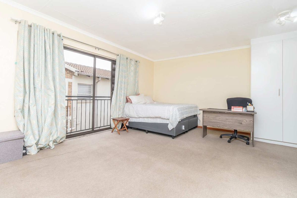 Spacious bedroom featuring neutral walls, carpet flooring, a built-in wardrobe, and a sliding glass door leading to a private balcony.