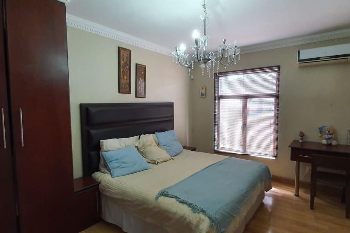 A well-maintained bedroom featuring laminate flooring, built-in cupboards, crown molding, and an integrated air conditioning unit.