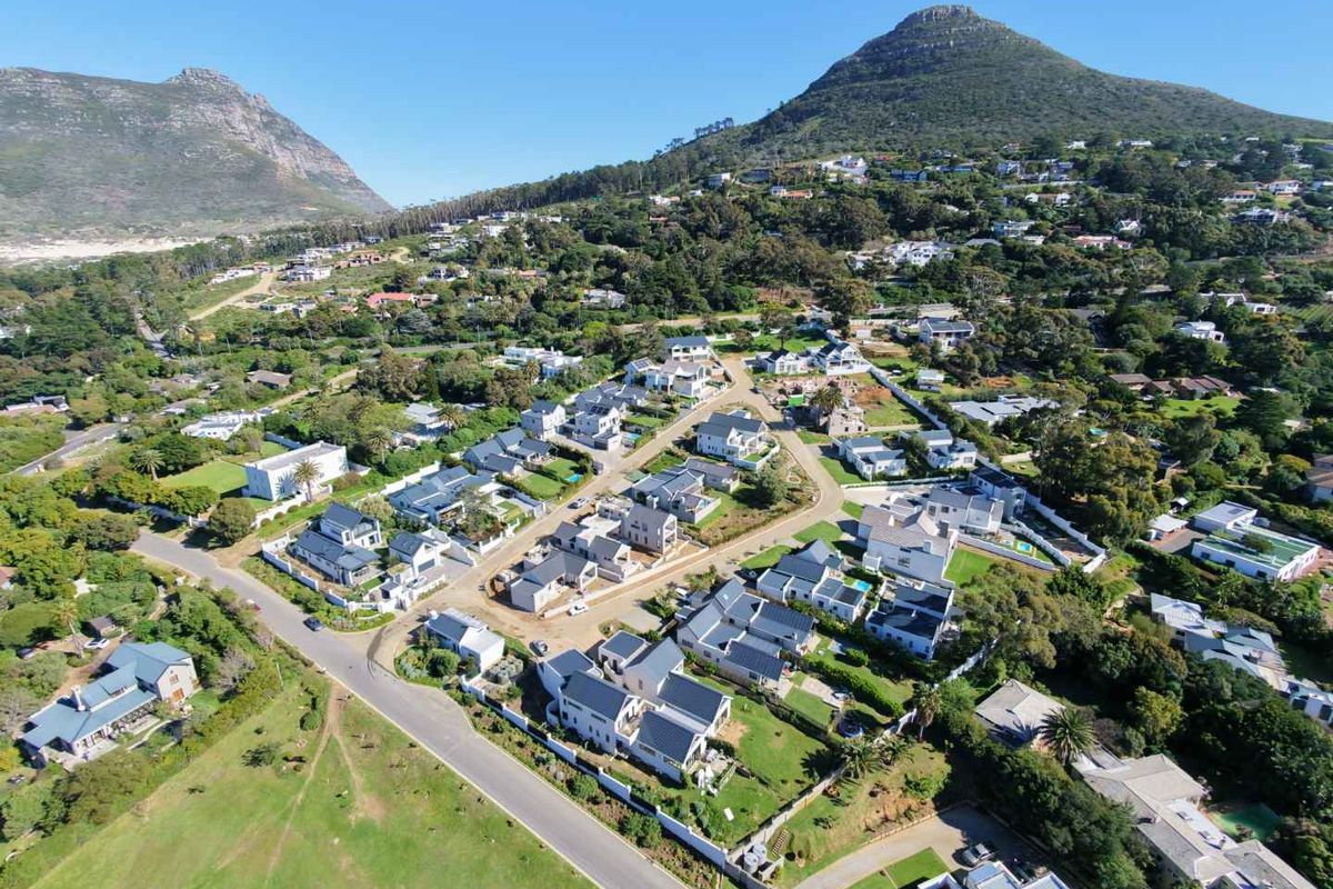 An aerial view of a residential estate development nestled in a scenic valley with mountain views and established landscaping.