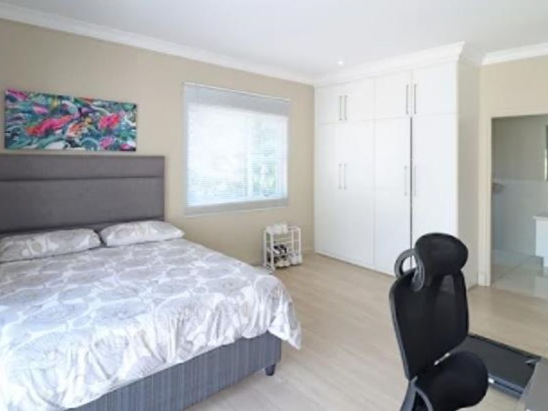 Spacious bedroom featuring light laminate flooring, ample built-in cupboard storage, and direct access to an en-suite bathroom.