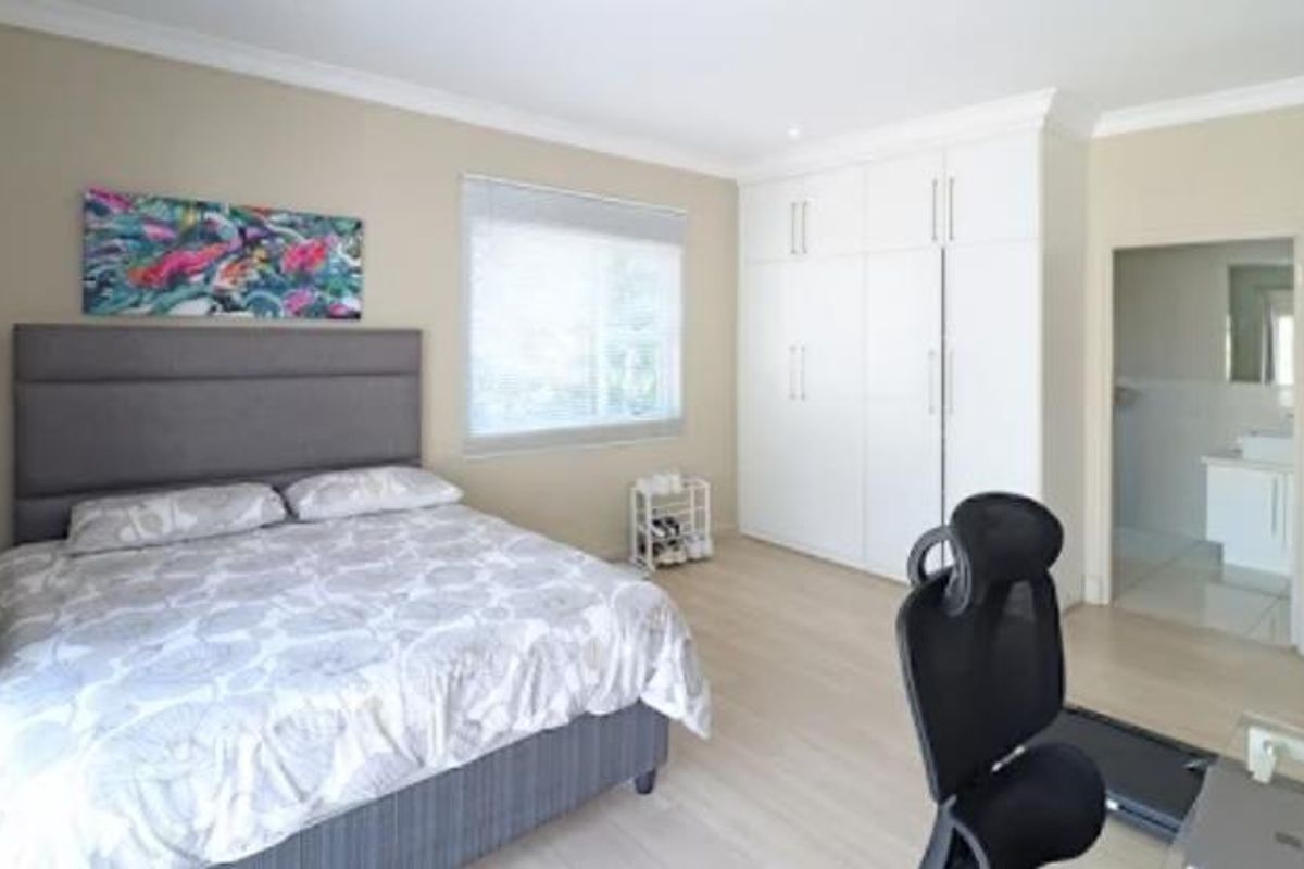 Spacious bedroom featuring light laminate flooring, ample built-in cupboard storage, and direct access to an en-suite bathroom.