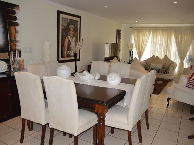 Open-plan living and dining area featuring tiled flooring, recessed lighting, and large sliding doors leading to an outdoor space.