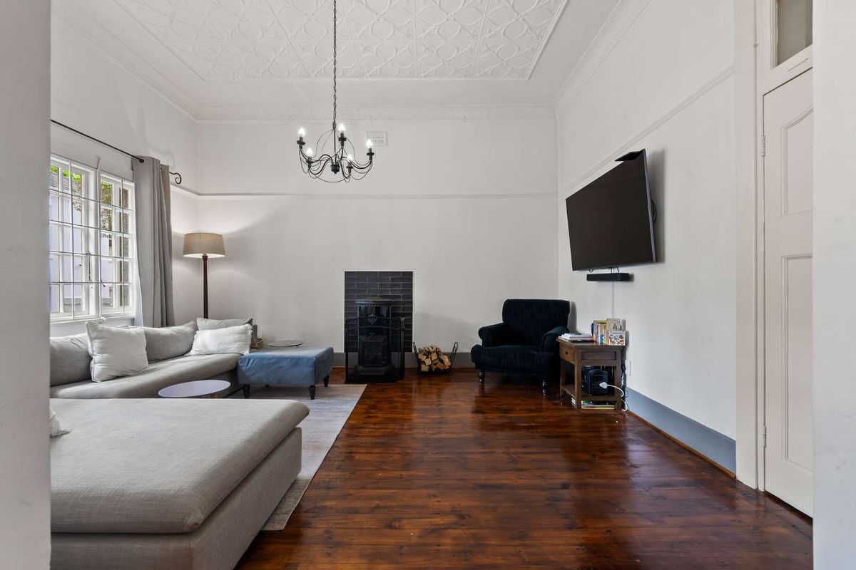 Spacious living room featuring polished hardwood floors, a decorative ceiling, and a fireplace with a tiled surround.