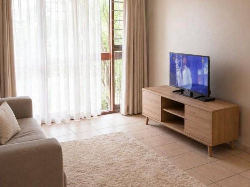 A neutrally decorated living room featuring tiled flooring and a large sliding glass door providing natural light and access to the exterior.