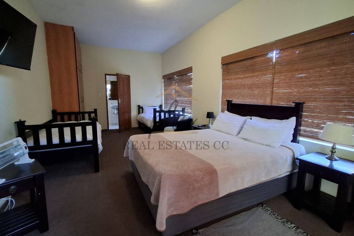 Spacious bedroom featuring carpeted flooring, built-in wardrobe, and an en-suite bathroom, providing comfortable accommodation with natural light through bamboo blinds.