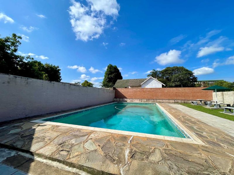 Outdoor swimming pool area featuring stone paving and brick boundary walls, providing a private recreational space for the apartment complex.