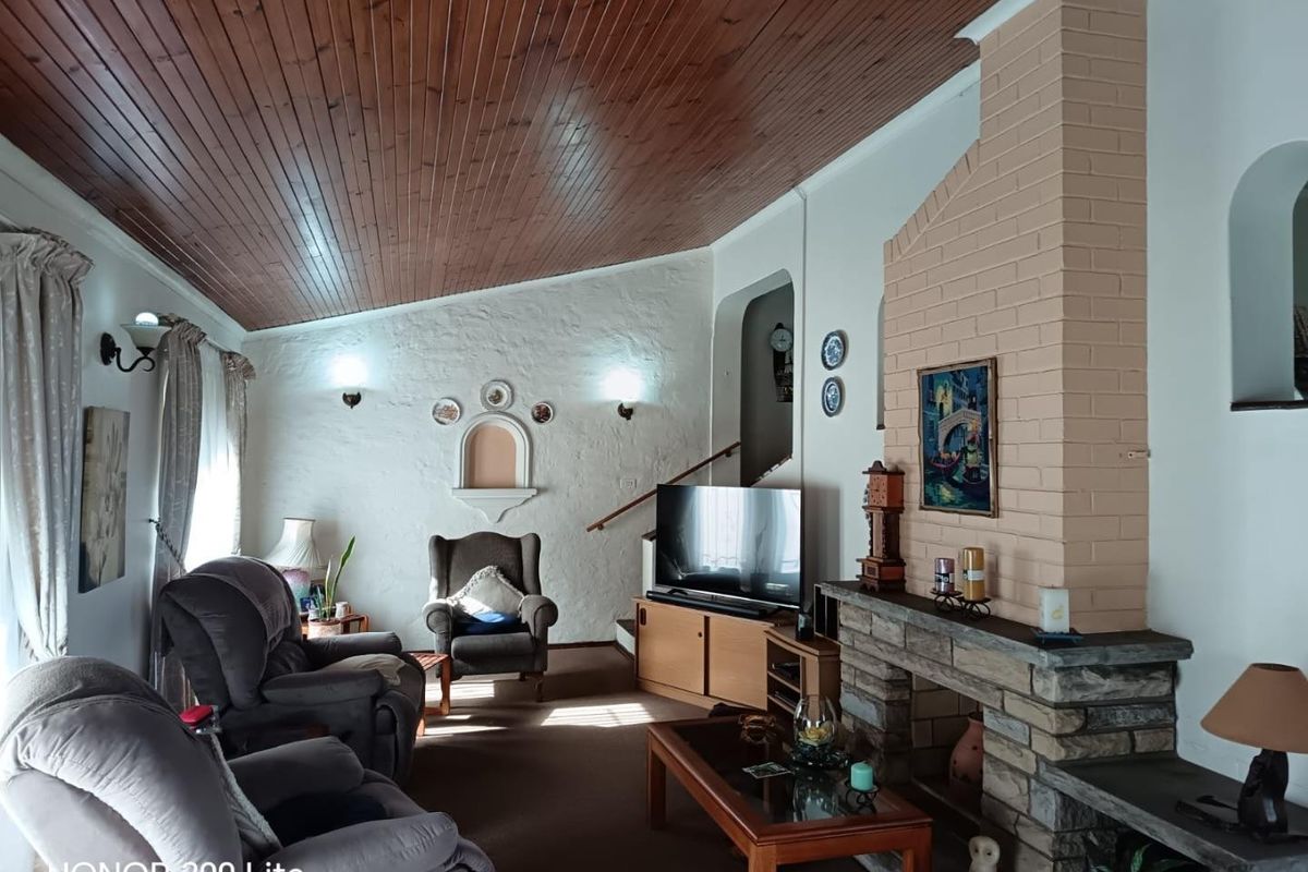 Spacious living room featuring a distinctive timber-clad vaulted ceiling, a prominent brick fireplace with stone detailing, and a charming arched wall niche.