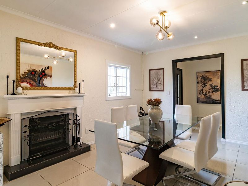 A well-maintained dining room featuring tiled flooring, a classic fireplace with a mantelpiece, and modern lighting fixtures.