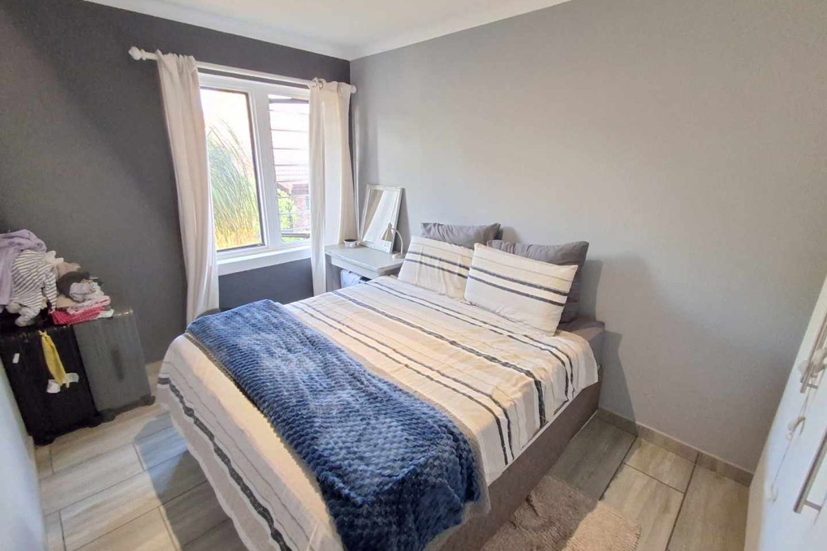 A well-maintained bedroom featuring neutral wall tones, tiled flooring, and a window providing natural light.