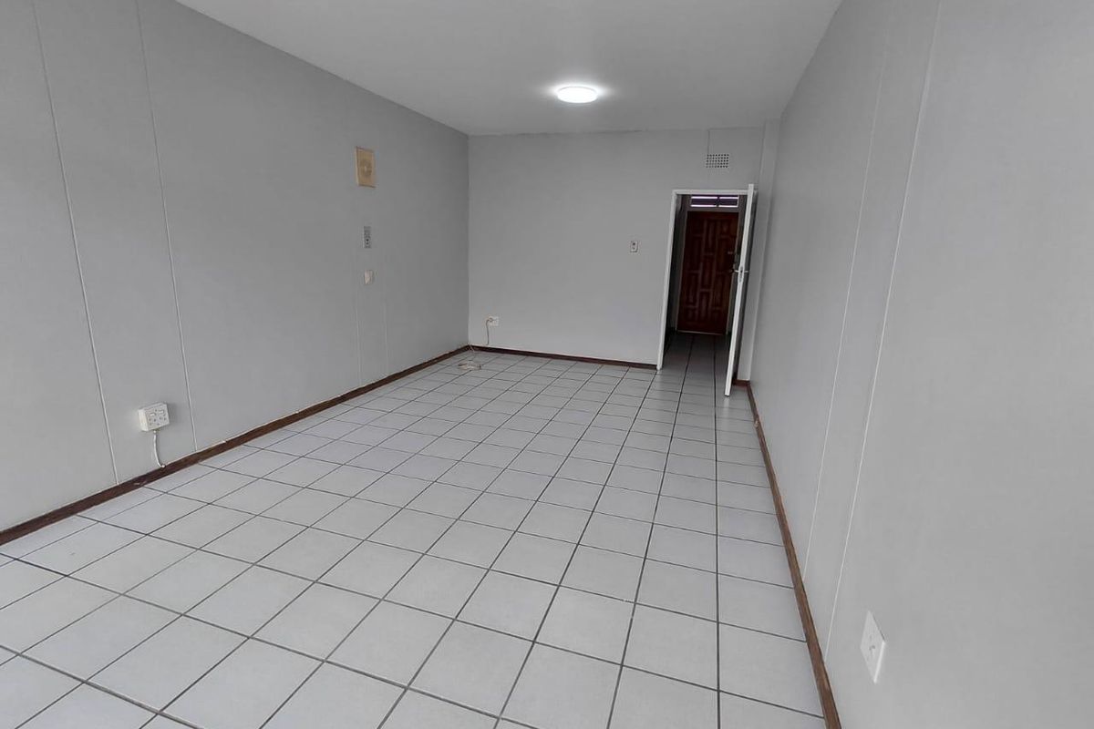 An empty, neutrally painted living area featuring tiled flooring and a simple ceiling light fixture, providing a blank canvas for interior design.