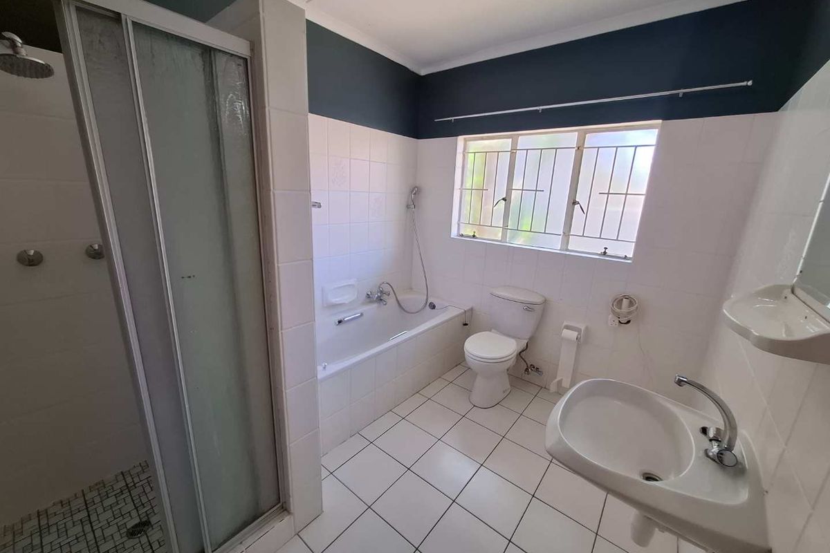 A functional bathroom featuring a separate shower enclosure, bathtub, pedestal basin, and toilet with tiled flooring and walls.