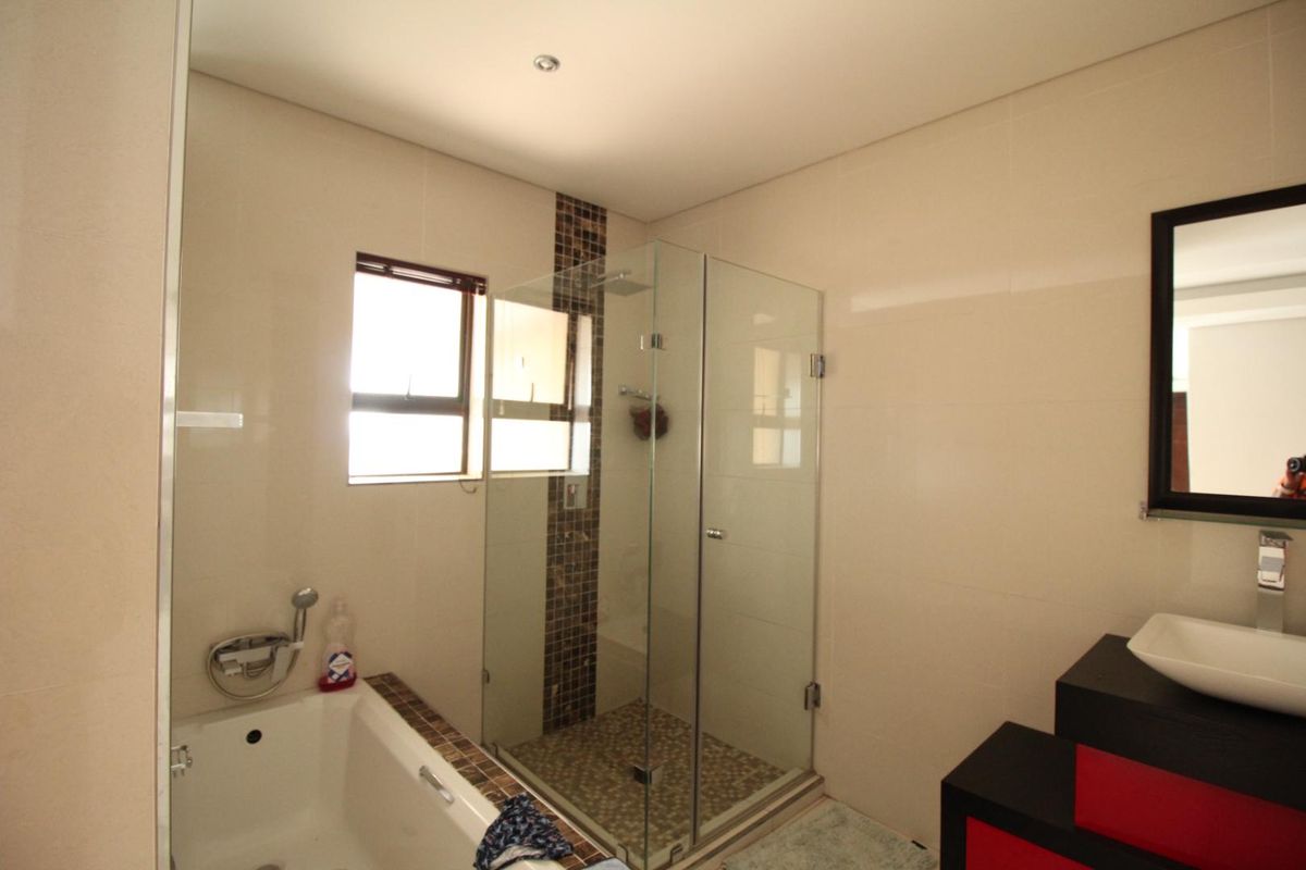 Modern bathroom featuring a glass-enclosed shower, a built-in bathtub with mosaic tile accents, and a contemporary vanity basin.
