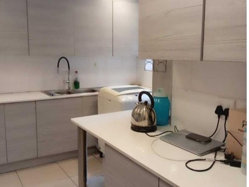 A functional kitchen featuring light wood-grain cabinetry, white quartz countertops, and tiled flooring, providing a clean and practical workspace.
