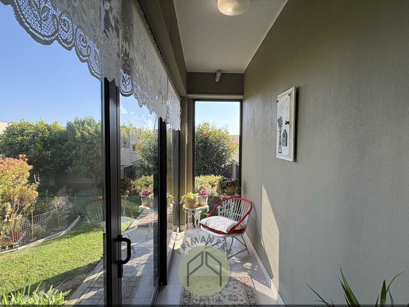 A covered patio area featuring tiled flooring and large sliding glass doors that provide direct access to the garden.