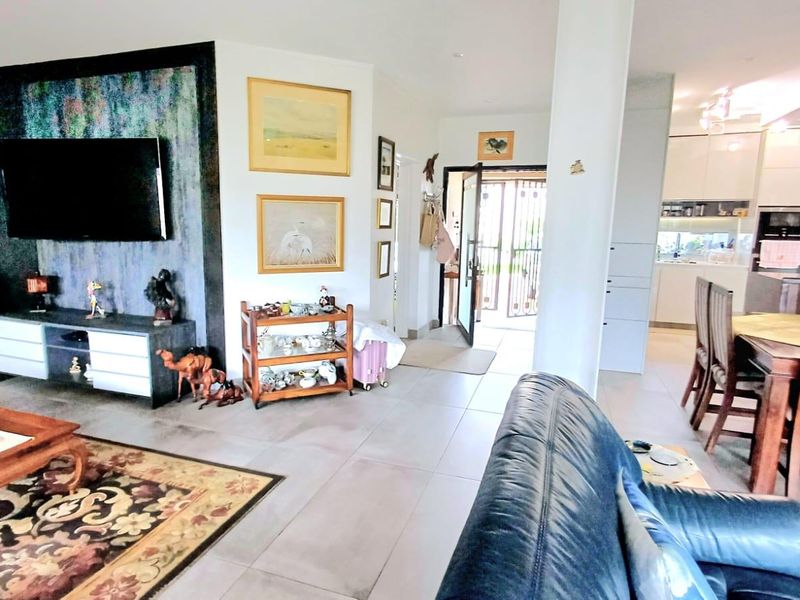 Spacious open-plan living area featuring tiled floors, a modern kitchen with built-in appliances, and direct access to the entrance.