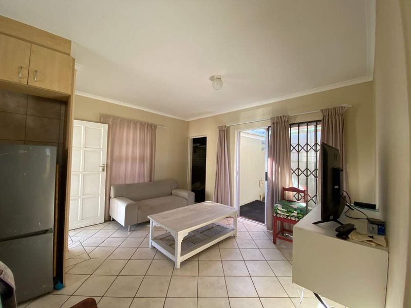 Open plan living area featuring tiled flooring and direct access to an outdoor space through a sliding glass door with security gate.