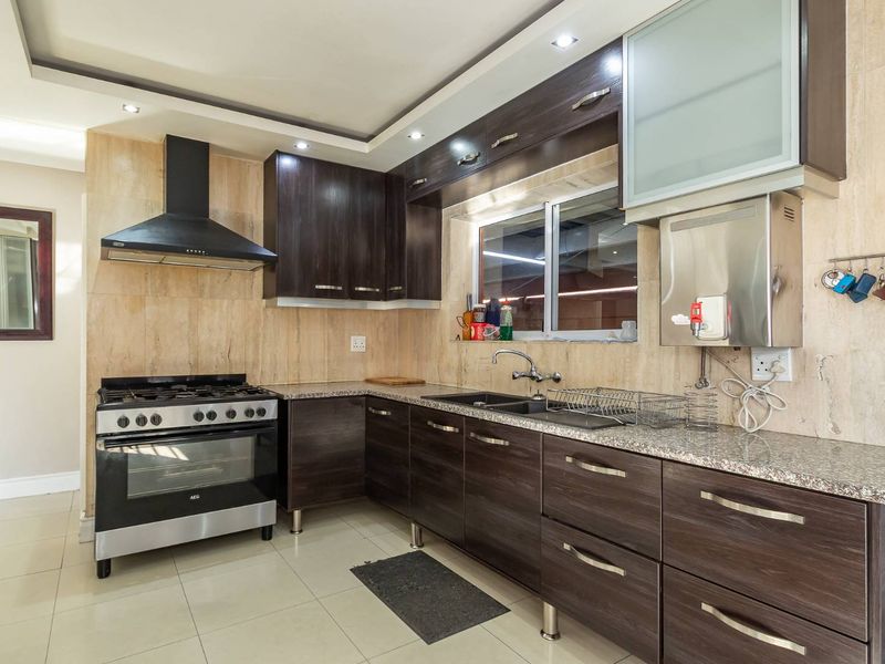 Modern kitchen featuring dark wood cabinetry, granite countertops, a gas stove with extractor fan, and a built-in water filtration system.