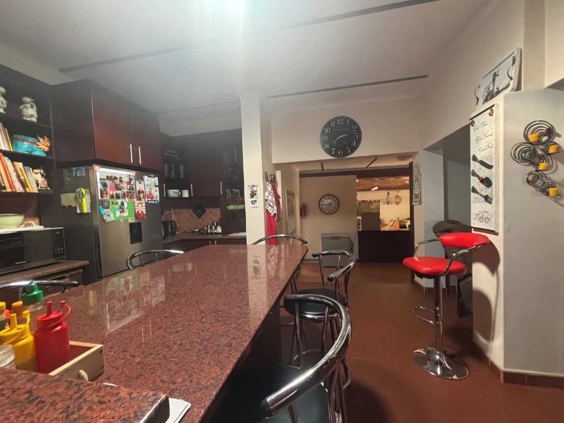 A functional kitchen featuring a large granite breakfast bar, dark wood cabinetry, and tiled flooring, offering a practical layout for daily meal preparation.