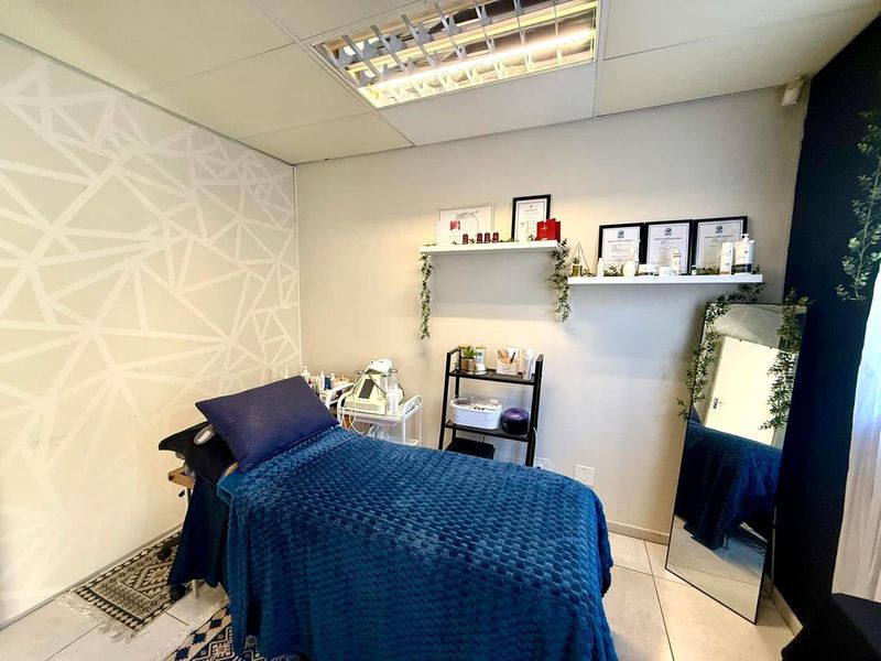 A well-maintained office or treatment room featuring tiled flooring, a suspended ceiling with recessed lighting, and built-in floating wall shelves.