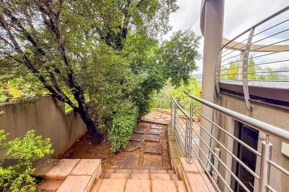 Outdoor staircase leading to a garden area, featuring stainless steel railings and paved steps alongside the building exterior.