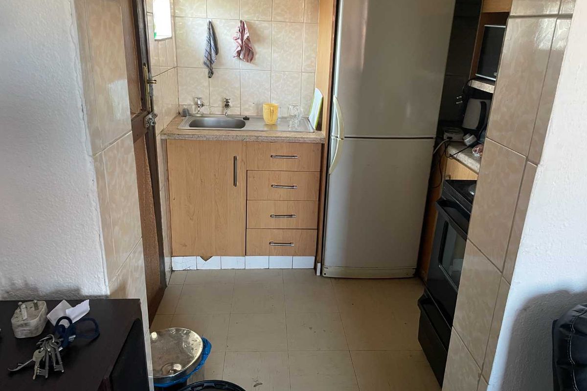 A compact, functional kitchen area featuring built-in cabinetry, a stainless steel sink, and tiled splashbacks.