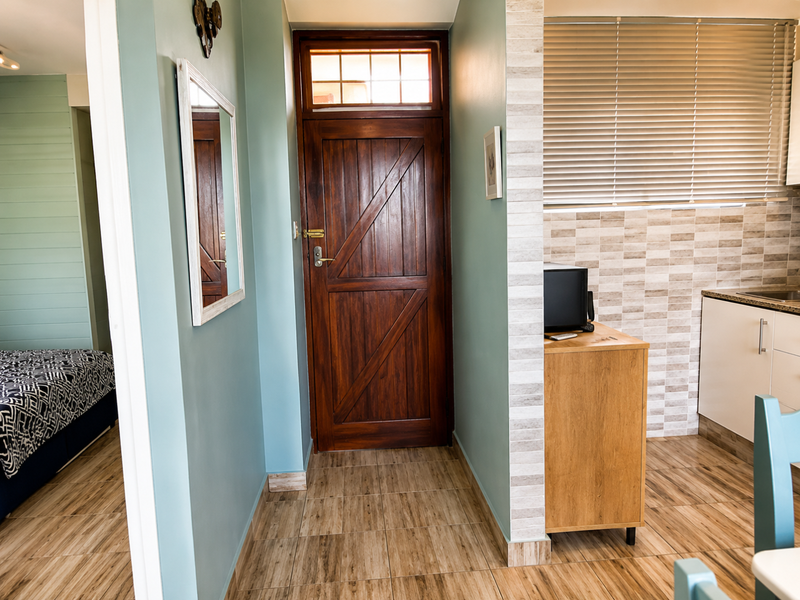 An inviting entryway featuring a solid timber front door with a transom window, leading into a space with tiled flooring and neutral wall tones.