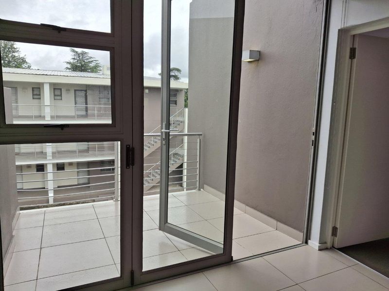 A clean, tiled balcony featuring modern aluminium sliding doors and a stainless steel balustrade, offering an open outdoor space.