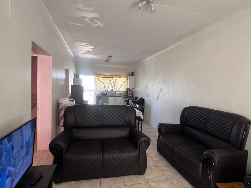 Open plan living and kitchen area featuring tiled flooring and visible ceiling maintenance requirements.