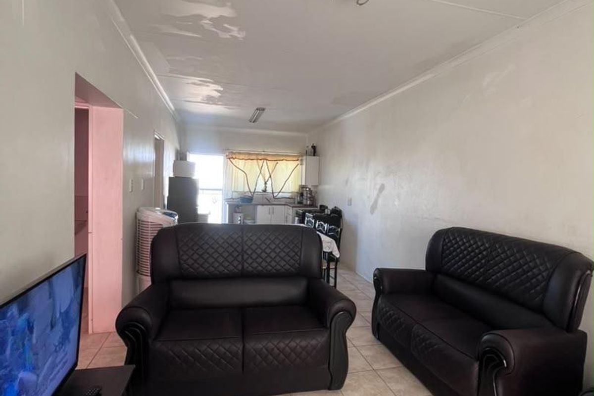 Open plan living and kitchen area featuring tiled flooring and visible ceiling maintenance requirements.