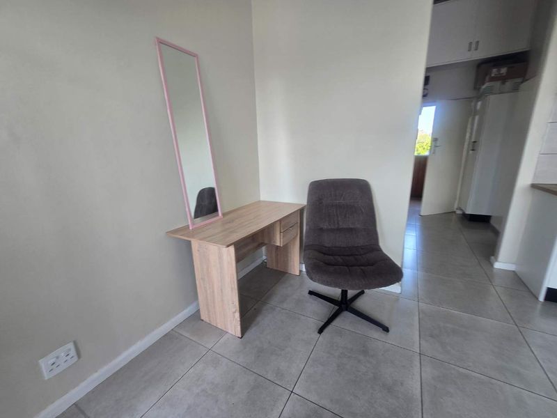 A neutral living area featuring tiled flooring and built-in electrical outlets, offering a versatile space for various furniture arrangements.