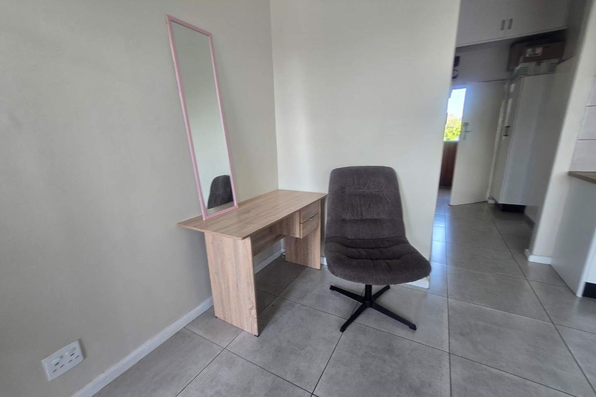 A neutral living area featuring tiled flooring and built-in electrical outlets, offering a versatile space for various furniture arrangements.