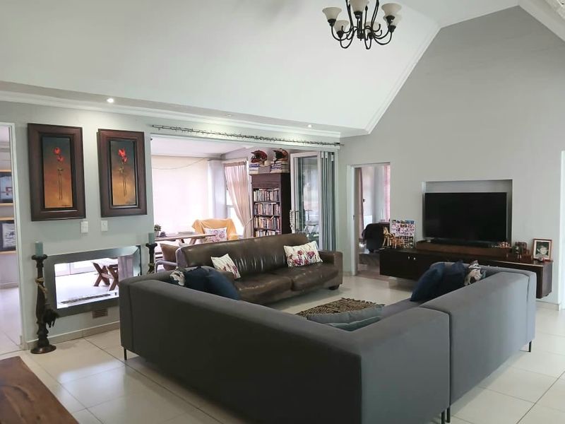 Spacious living room featuring a high vaulted ceiling, tiled flooring, a built-in fireplace, and a recessed television niche with access to an adjoining area.