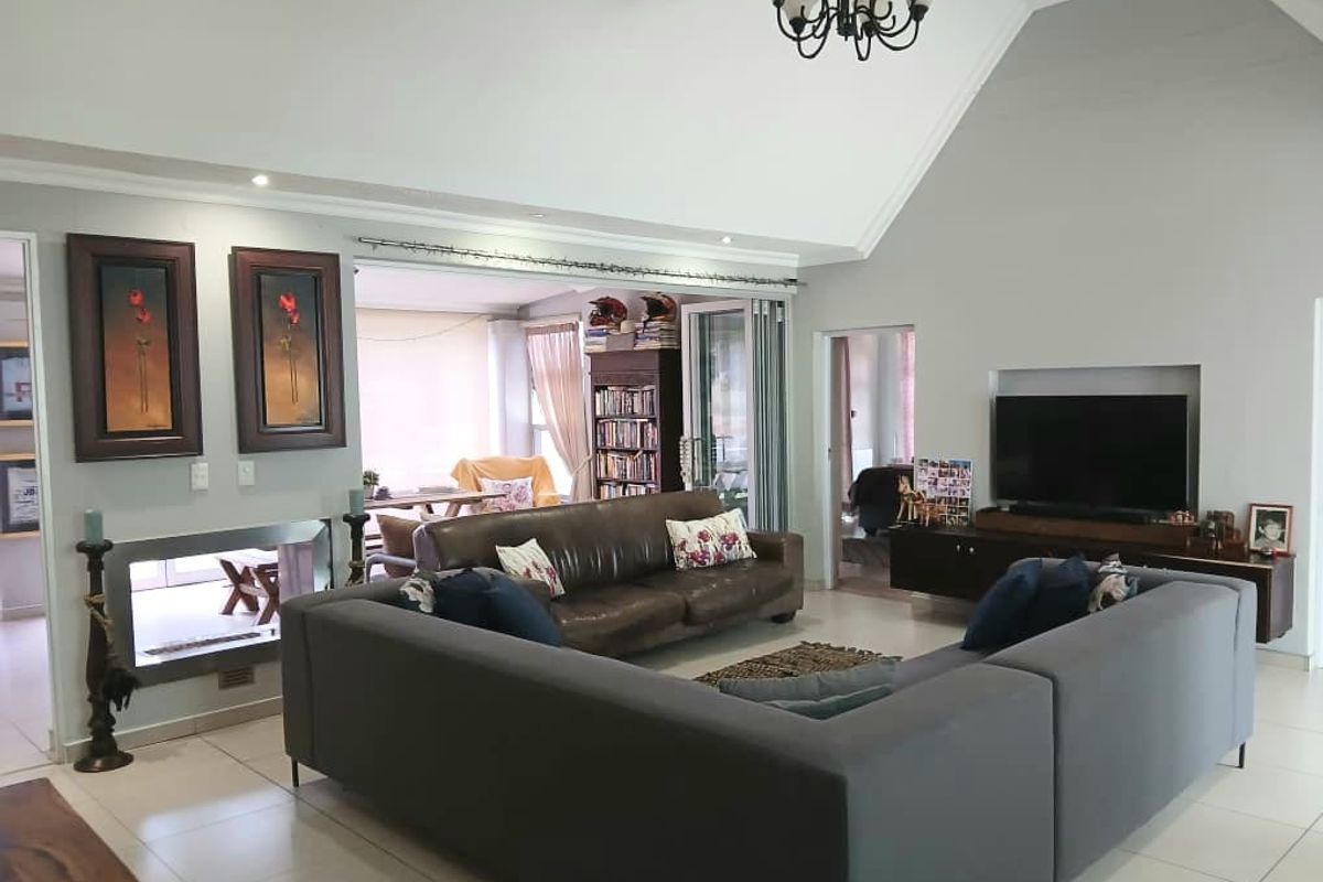 Spacious living room featuring a high vaulted ceiling, tiled flooring, a built-in fireplace, and a recessed television niche with access to an adjoining area.
