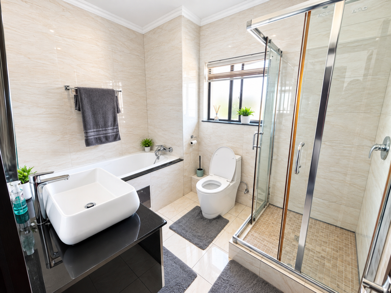 Modern bathroom featuring a vessel sink on a black vanity, a built-in bathtub, a separate glass-enclosed shower, and neutral wall tiling.