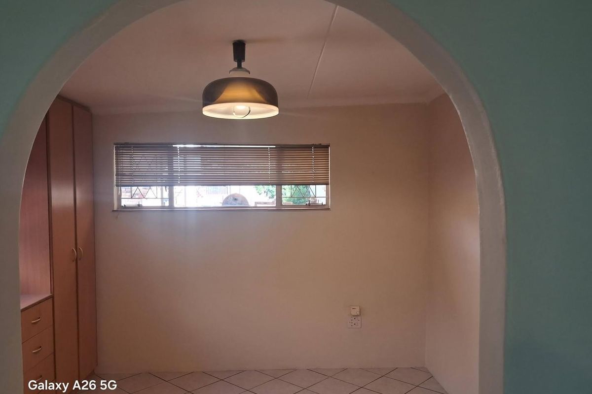 An empty bedroom featuring built-in cupboards, tiled flooring, and a distinctive arched entryway, providing a blank canvas for personalization.