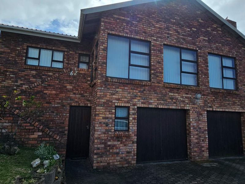 A double-storey face brick house featuring a double garage, paved driveway, and established garden, presenting a classic and durable exterior facade.