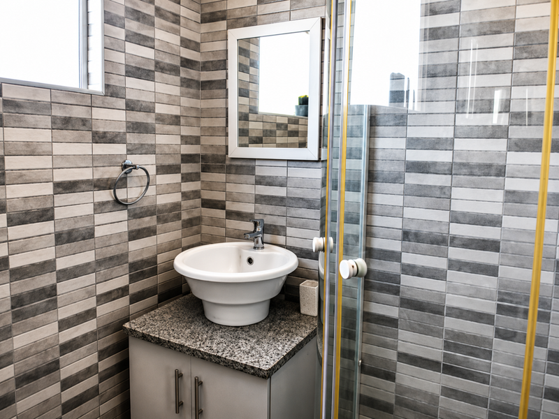 A modern bathroom featuring a vessel sink on a granite vanity, tiled walls, and a glass shower enclosure.