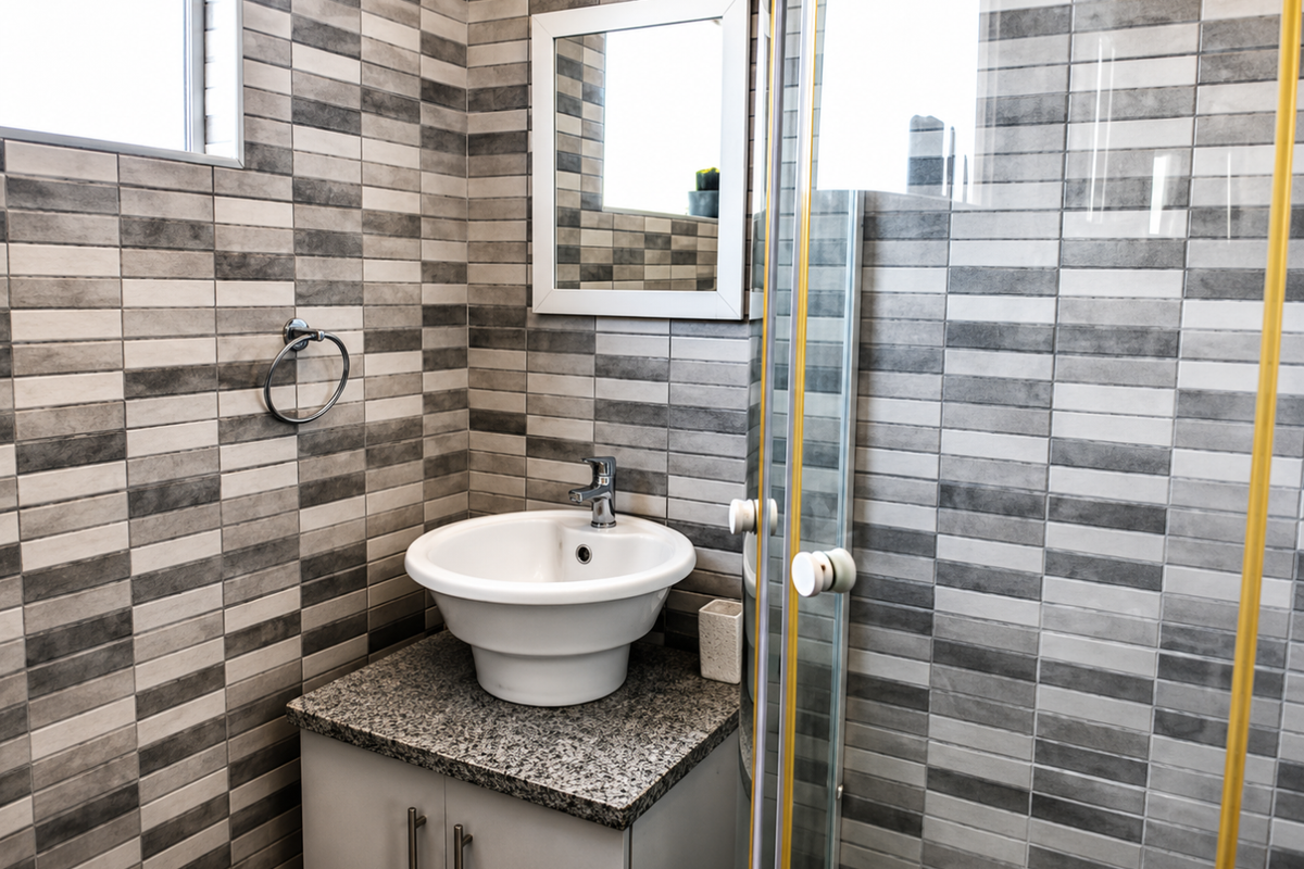 A modern bathroom featuring a vessel sink on a granite vanity, tiled walls, and a glass shower enclosure.