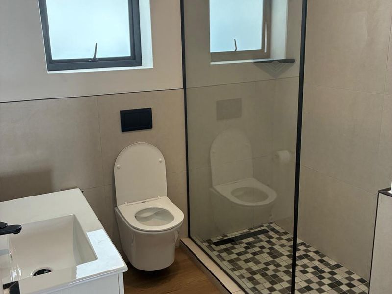 Modern bathroom featuring a walk-in shower with black frame, wall-hung toilet, and a sleek vanity basin with contemporary finishes.