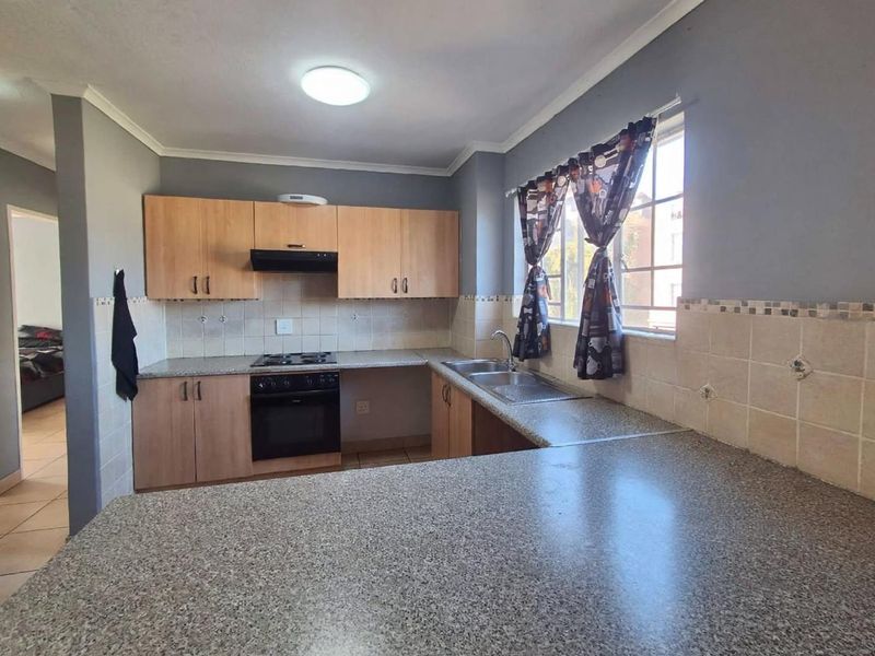 Functional kitchen featuring laminate cabinetry, built-in oven with extractor fan, double bowl sink, and ample granite-look countertop space.