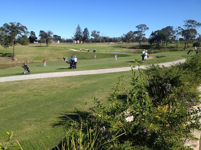 A scenic view of a well-maintained golf course featuring lush green fairways, landscaped grounds, and a water feature.
