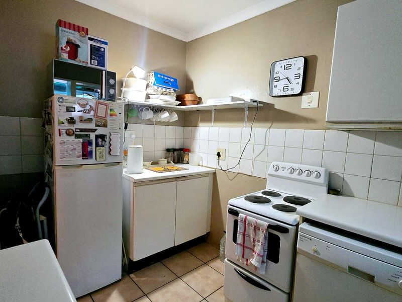 Compact kitchen featuring a freestanding electric stove, tiled backsplash, and functional cabinetry, offering a practical layout for daily meal preparation.