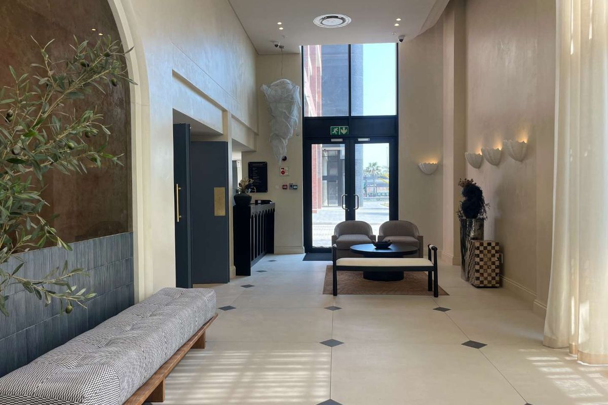 Elegant apartment building entrance lobby featuring high ceilings, tiled flooring with decorative inlays, and modern wall sconce lighting.