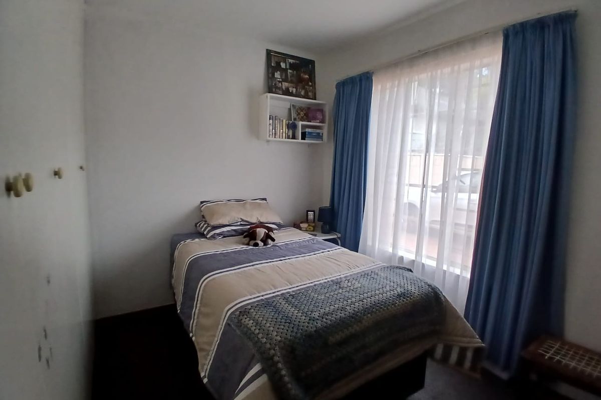 A functional bedroom featuring built-in cupboards and a window with curtain tracks, providing natural light and storage space.