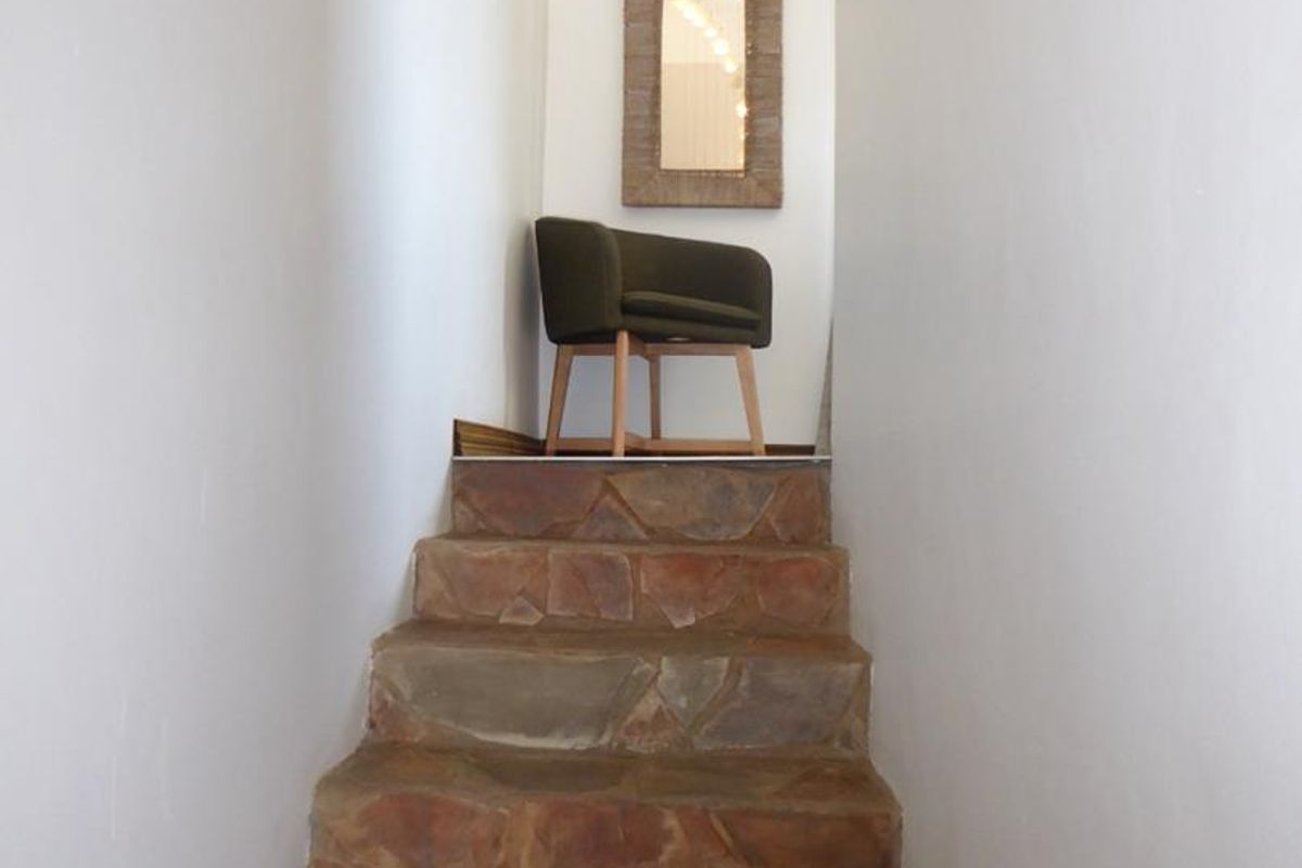 A narrow hallway featuring a rustic stone staircase leading to an upper landing.